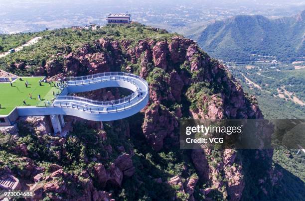 Aerial view of tourists walking on the glass skywalk at Fuxi Mountain tourism area on June 12, 2018 in Xinmi, Henan Province of China. The round...