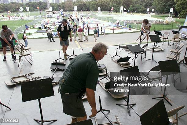 Chairs and music stands are removed after a New York Philharmonic concert was canceled in Central Park. The park was closed for the night to permit...