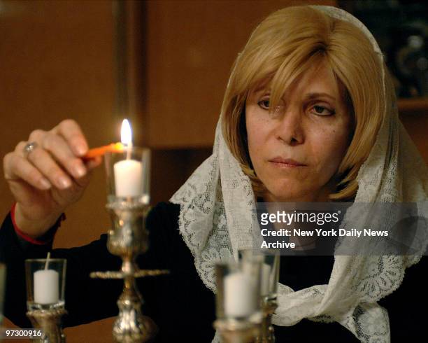 Chana Taub lights candles at sundown. She said her husband kept her awake by "bumping furniture" on his side of wall splitting their home into two....