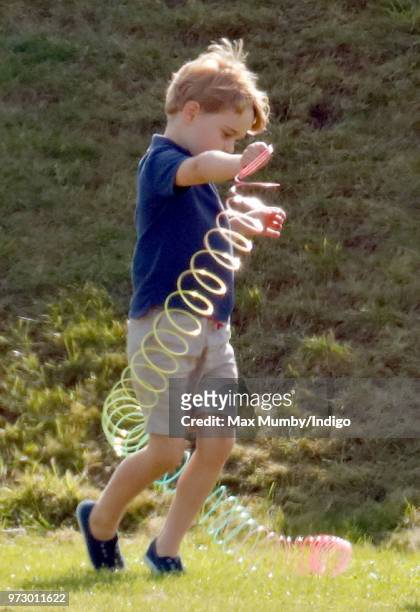 Prince George of Cambridge plays with a Slinky toy as he attends the Maserati Royal Charity Polo Trophy at the Beaufort Polo Club on June 10, 2018 in...