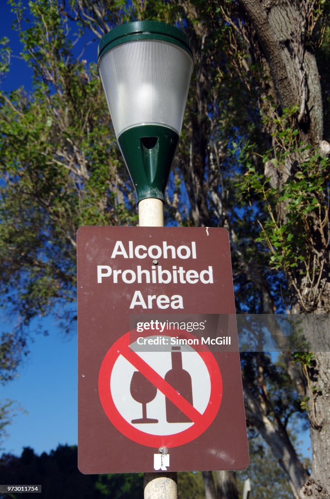 'Alcohol prohibited area' sign on a street light in a public park