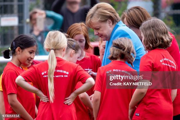 German Chancellor Angela Merkel talks with children taking part in the event "Sports and Integration" as she visits the "SV Rot-Weiß Viktoria Mitte...