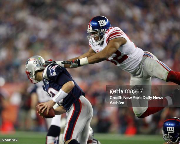New York Giants' defensive end Michael Strahan goes airborne as he puts pressure on New England Patriots' quarterback Tom Brady during Super bowl...