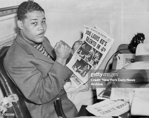 Joe Louis reads about victory over Tony Galento in the Daily News.