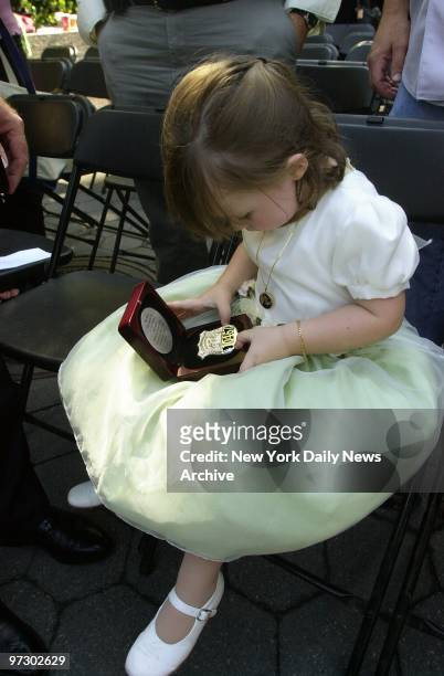 Three-year-old Patricia Smith looks at the shield that belonged to her mother, Police Officer Moira Smith, the only woman among 23 NYPD cops killed...