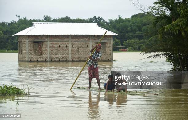 Indian villagers cross flooded area on a bamboo raft at a village in Dharmanagar on June 13 in the northeastern state of Tripura.