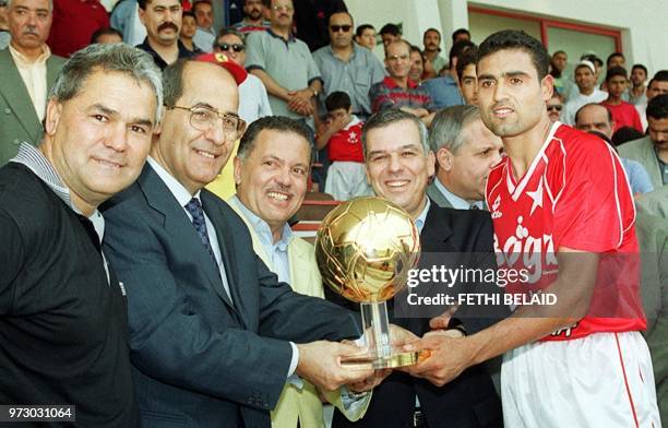 Director of Lebanon's newspaper Erriadh, Said Kabrissi gives the Arab Golden Ball trophy to Tunisian player of the Star of Sahel's soccer team, Kais...