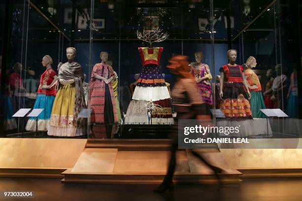 Museum employee walks past a display of dresses owned by Frida Kahlo, with the central dress: 'Tehuana outfit' Huipil before 1954, cotton muslin with...