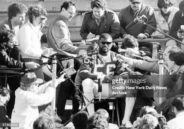 New York Giants' linebacker Lawrence Taylor is besieged by microphones at a news conference.