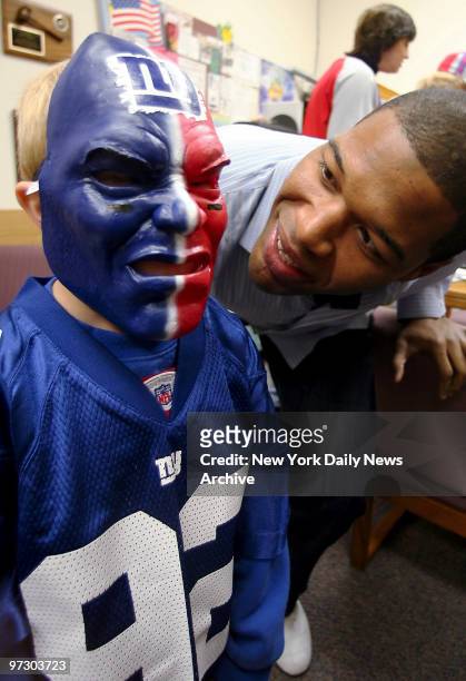 New York Giants' Michael Strahan checks out Luke Falkenstern's Giants' mask at the Norwood Elementary School in Norwood, N.J. The first-grader won...