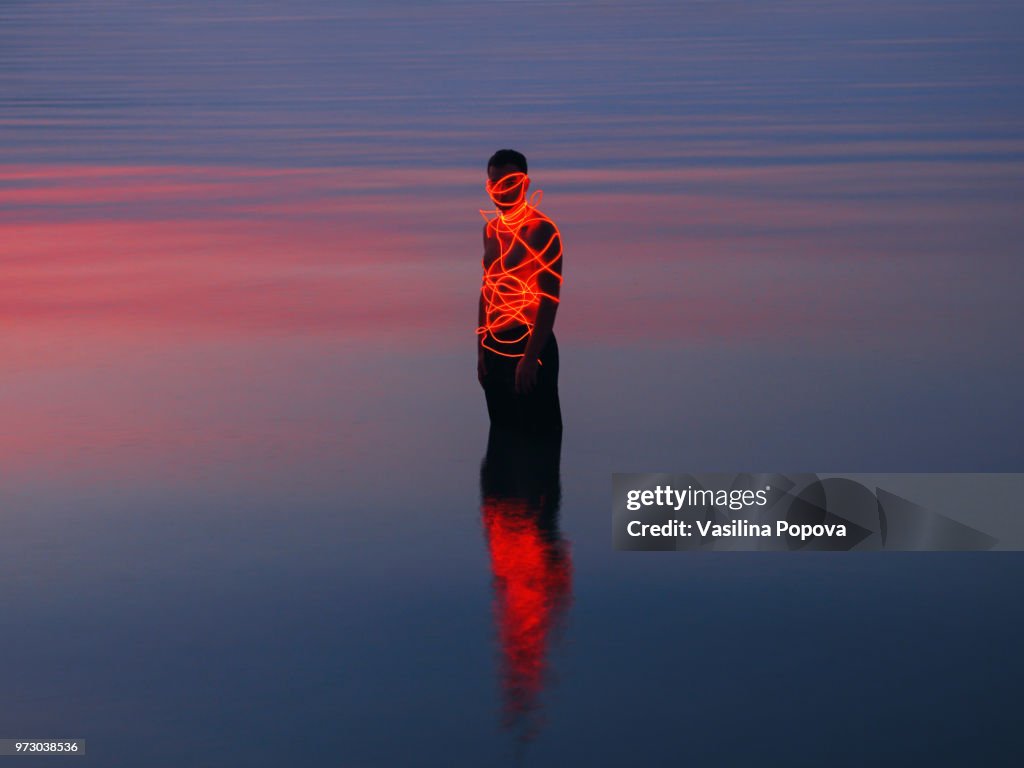 Man entangled with neon wires against sea background