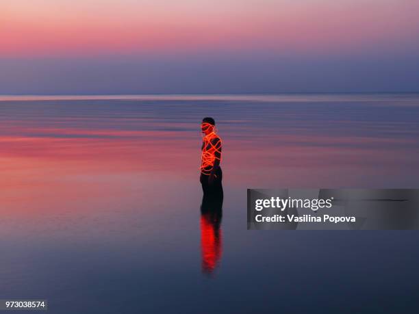 Man entangled with neon wires against sea background