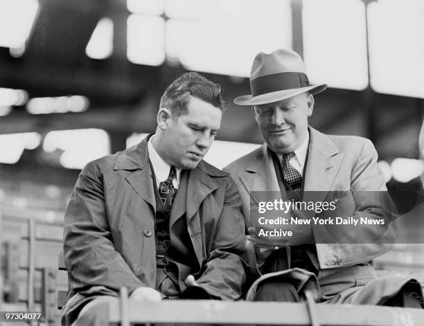 Tim Mara, owner of grid New York Giants, checks over race card with plunger Art Rooney, owner of grid Pittsburgh Pirates, at Ebbets Field. Meanwhile,...