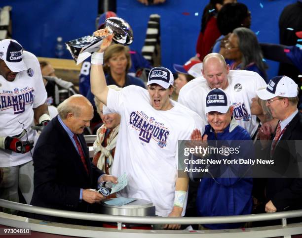 New York Giants' quarterback Eli Manning holds up the Vince Lombardi trophy as he stands next to head coach Tom Coughlin after the Giants pulled off...