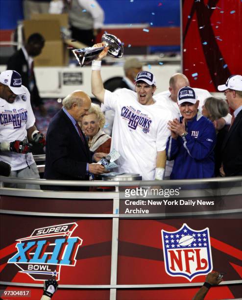 New York Giants' quarterback Eli Manning holds up the Vince Lombardi trophy as he stands next to head coach Tom Coughlin after the Giants pulled off...