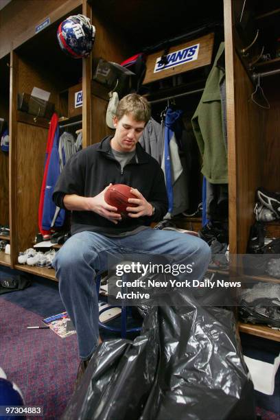New York Giants' quarterback Eli Manning looks at one of his game balls as he packs up some of his personal belongings in the locker room at Giants...