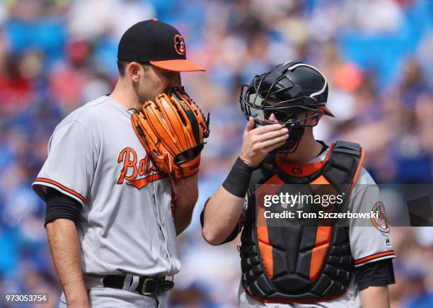 Darren O'Day of the Baltimore Orioles talks to Chase Sisco on the mound as he comes in from the bullpen to pitch in the eighth inning during MLB game...