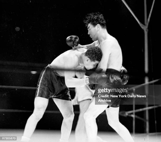 Max Schmeling versus Joe Louis I at Yankee Stadium., Brutally buffeted by Max's unmerciful rights, a groping Louis hangs on desperately to his...