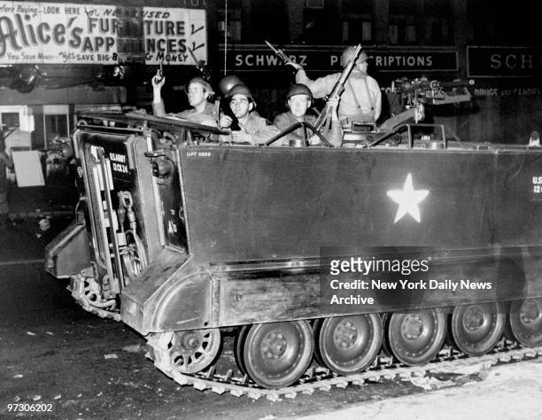 Soldiers in an armored personnel carrier patrol the streets of Newark during race riots.