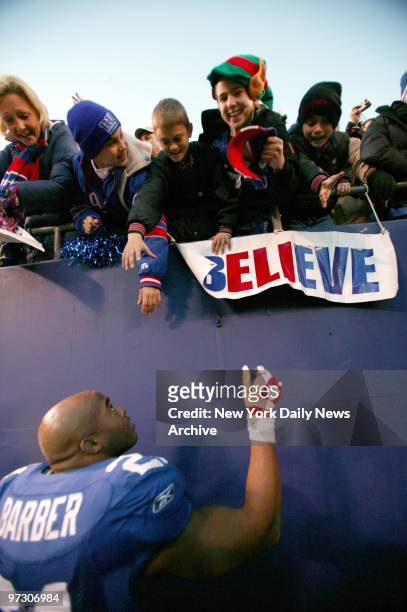 New York Giants' running back Tiki Barber greets fans while leaving the field after what was likely his final home game at Giants Stadium before his...
