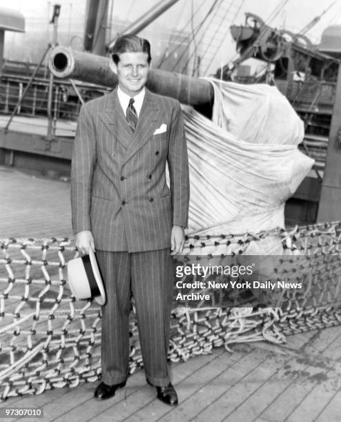 John F. Kennedy, [sic]son of the U.S. Ambassador to Great Britain, arriving in New York aboard the SS Mauretania. He stands next to an anti-aircraft...