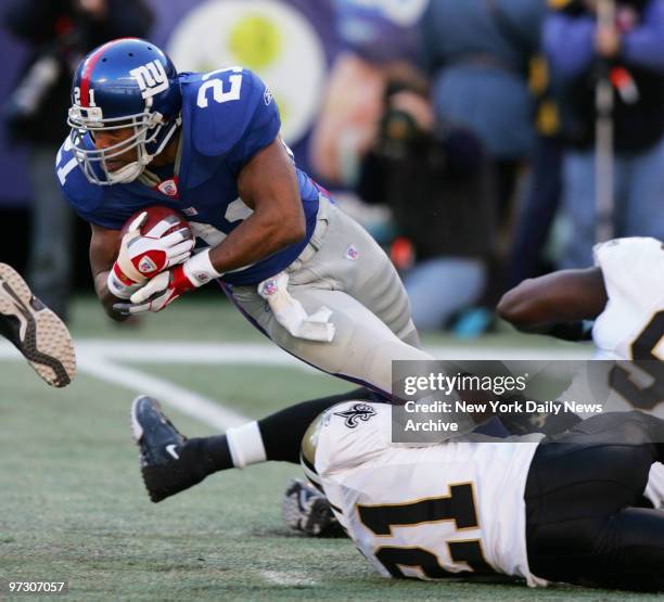 New York Giants' running back Tiki Barber is taken down by New Orleans Saints' cornerback Jason Craft during a game at Giants Stadium. The Christmas...