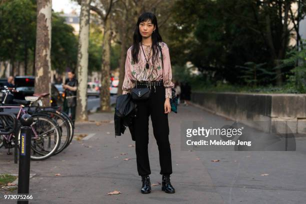 Model Gao Jie weasr a pink floral top, black pants and boots, and a black YSL bag during Paris Fashion Week Spring/Summer 2018 on September 27, 2017...