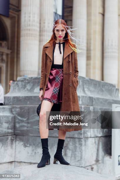 Model Teddy Quinlivan exits the Margiela show in the white hair extensions and red lipstick and wears a long brown suede coat, open black top, red...