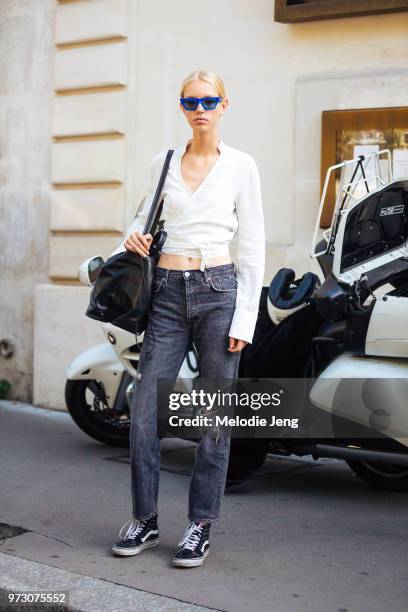 Model Jessie Bloemendaal wears blue sunglasses, a white wrap top, jeans, and black Vans sneakers during Paris Fashion Week Spring/Summer 2018 on...