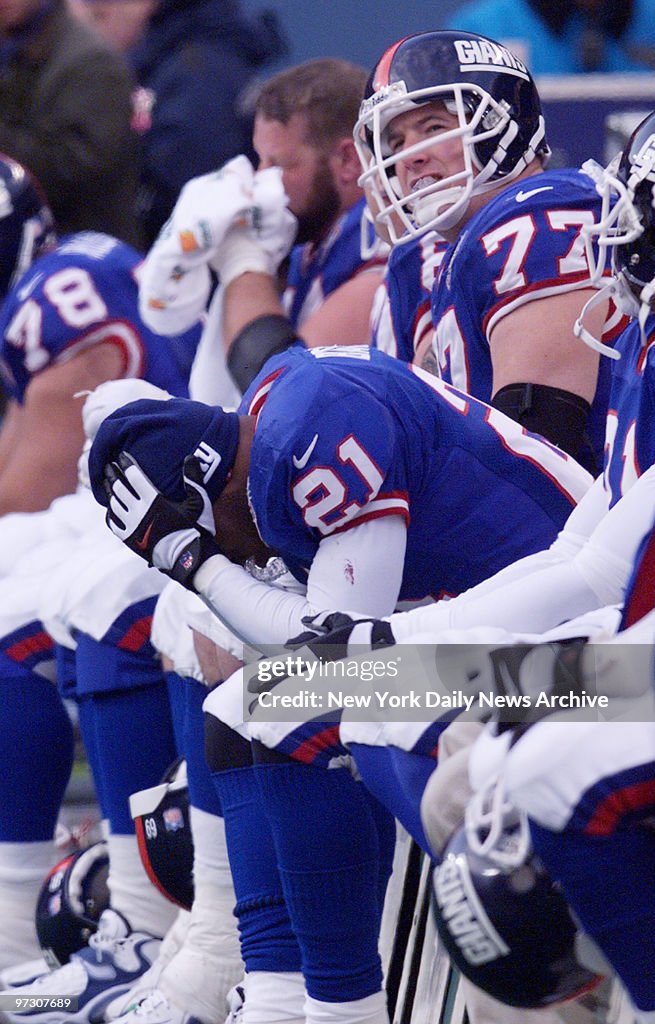 New York Giants' Tiki Barber holds his head on the bench as
