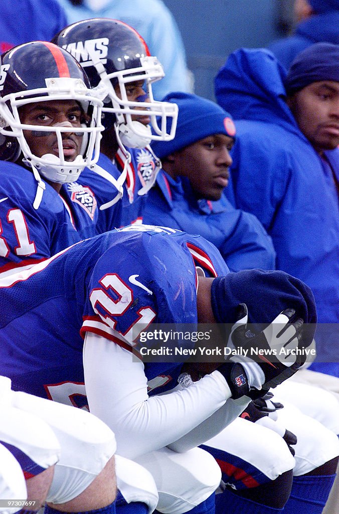 New York Giants' Tiki Barber holds his head on the bench as