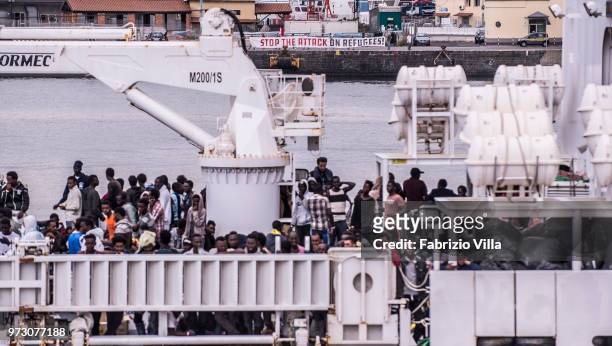 Migrants disembark the Italy's coastguard ship Diciotti at the port of Catania. ÂStop the attak on refugeesâ: a banner of several demonstrators in...