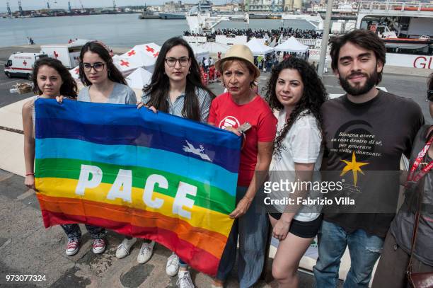 Demostrators holding a flag saying 'PEACE' while migrants disembark the Italy's coastguard ship Diciotti at the port of Catania on June 13, 2018 in...