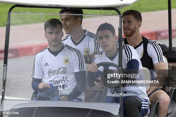 Argentina's midfielder Cristian Pavon drives a cart with teammates defender Nicolas Taglafico , forward Paulo Dybala and defender Cristian Ansaldi as...