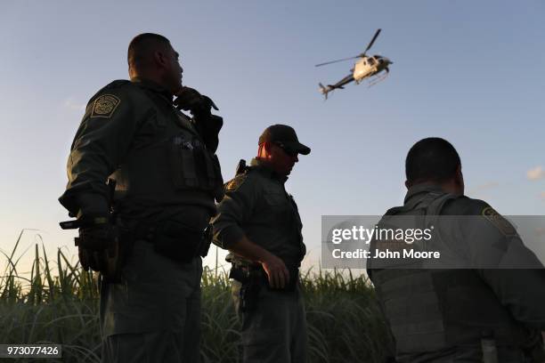 Border Patrol agents watch over a group of undocumented immigrants after chasing them through a cane field near the U.S.-Mexico Border on June 12,...