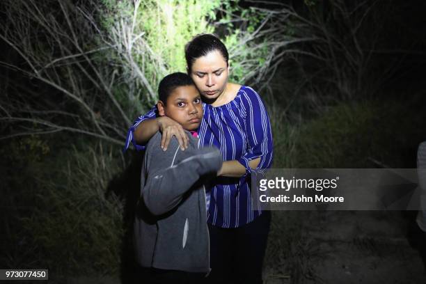 Border Patrol spotlight shines on a terrified mother and son from Honduras as they are found in the dark near the U.S.-Mexico border on June 12, 2018...