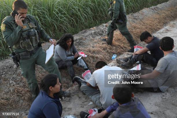 Border Patrol agents watch over a group of undocumented immigrants after chasing and apprehending them in a cane field near the U.S.-Mexico Border on...