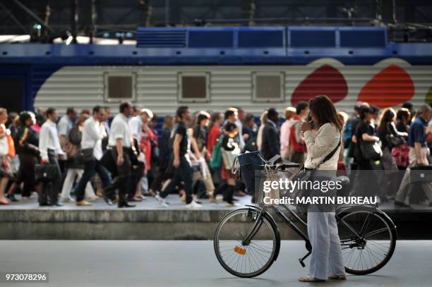 Bicycle rider lights a cigarette on a platform as a crowd of passengers walks past a train at the Saint-Lazare train station, on June 10, 2008 in...