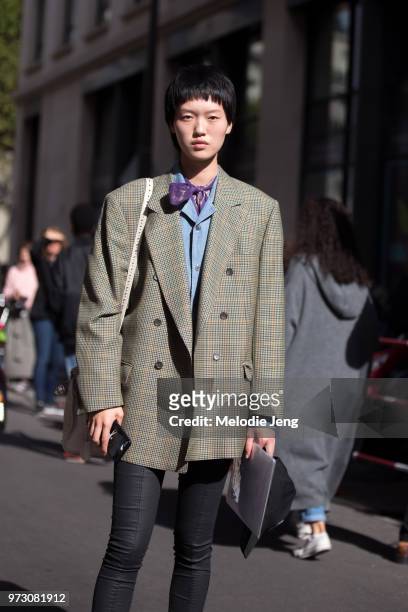 Chinese model Shujing Zhou wears a Balenciaga oversized check jacket, black pants, a blue shirt, and purple scarf during Paris Fashion Week...