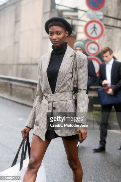 Senegalese model Mame Thiane Camara wears a black beret, tan belted check jacket, and blue turtleneck during Paris Fashion Week Spring/Summer 2018 on...