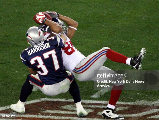 New York Giants' wide receiver David Tyree pins the ball to his helmet as he catches a 32-yard pass late in the fourth quarter of Super Bowl XLII...