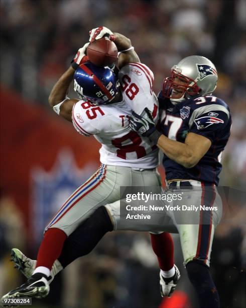 New York Giants' wide receiver David Tyree pins the ball to his helmet as he catches a 32-yard pass late in the fourth quarter of Super Bowl XLII...