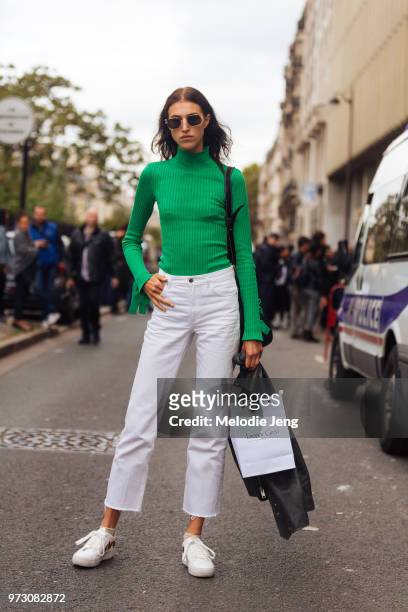 Model India Ruiterman wears a green sweater, white jeans, and white sneakers during Paris Fashion Week Spring/Summer 2018 on October 2, 2017 in...