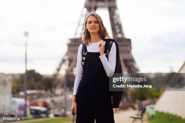 Model Vanya Dakovic poses infront of the Eiffel tower and wears black overalls over a white shirt during Paris Fashion Week Spring/Summer 2018 on...