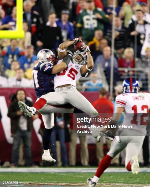 New York Giants' wide receiver David Tyree pins the ball to his helmet as he catches a 32-yard pass late in the fourth quarter of Super Bowl XLII...