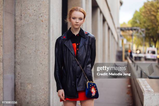 Model Lily Nova wears a black leather jackets with hearts and a small blue purse with an embroidered baby cupid after the Miu Miu show during Paris...
