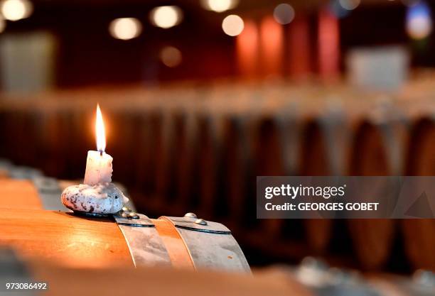 This photo taken on May 14, 2018 shows a burning candle on a wine barrel used to light sulfur pastilles in the wine cellar of the Chateau Rayne...