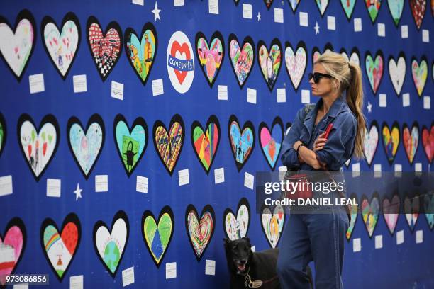 Woman looks at a wall of hearts with drawings and messages of support for the 71 people who died in the Grenfell fire, outside the Notting Hill...