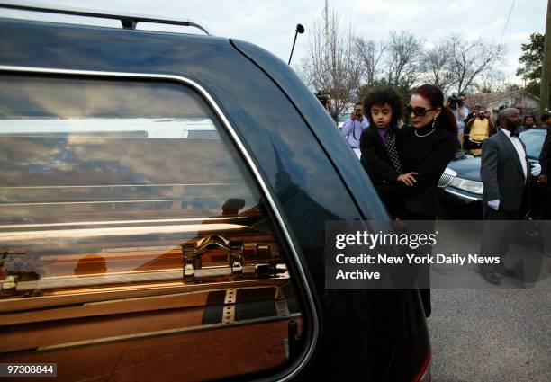 Tomi Rae Hynie and her son, James Brown 2d, look into a hearse containing the coffin of soul legend James Brown as it pulls away after a private...