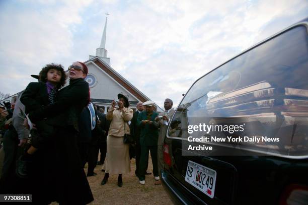 Tomi Rae Hynie holds her son, James Brown 2d, next to a hearse containing the coffin of soul legend James Brown as it pulls away after a private...